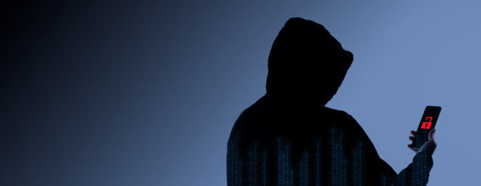 Hacker Anonymous and face mask with smartphone in hand.