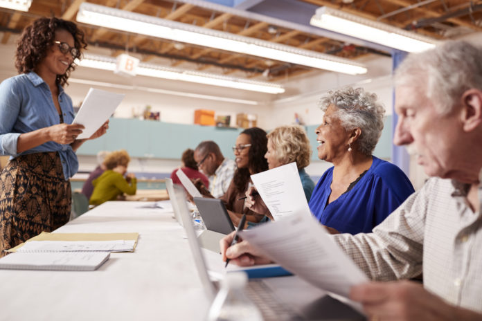 Group Of Retired Seniors Attending IT Class In Community Centre With Teacher